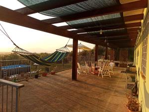 eine Terrasse mit einer Hängematte sowie einem Tisch und Stühlen in der Unterkunft Villa Tramonto in Alghero