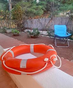 un salvavidas naranja y una silla en un patio en Antonia’s Home, en San Domino