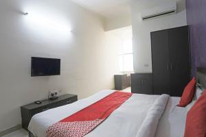 een slaapkamer met een bed en een tv aan de muur bij Flagship Aman Hotel in Indirapuram