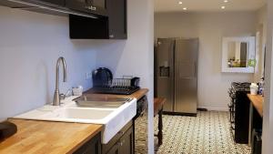 a kitchen with a sink and a refrigerator at Villa Colin, la tête dans les bois, à deux pas de la mer, classée 4 étoiles in Yport