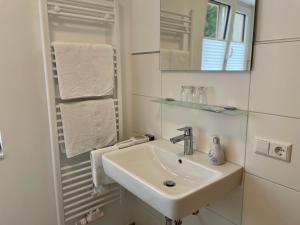 ein Badezimmer mit einem Waschbecken, einem Spiegel und Handtüchern in der Unterkunft Gasthaus Zur Erle in Simonswald