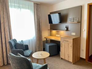 ein Hotelzimmer mit einem Schreibtisch, Stühlen und einem TV in der Unterkunft Gasthaus Zur Erle in Simonswald
