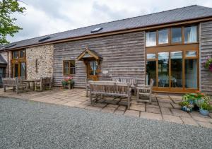 a patio with benches and tables in front of a building at Hafan Llewelyn in Builth Wells