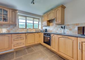 a large kitchen with wooden cabinets and a window at Canoldy in Builth Wells