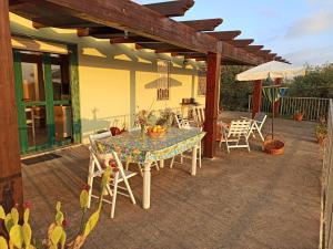 um pátio com uma mesa, cadeiras e um guarda-sol em Villa Tramonto em Alghero
