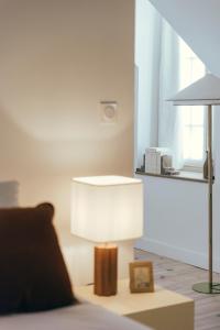 una lámpara sentada en una mesa junto a una cama en La Papote, en Bourron-Marlotte
