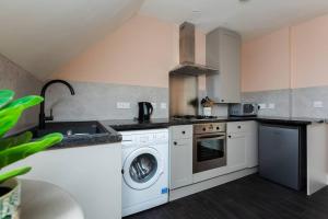a kitchen with a washing machine and a sink at Queenie - Charming one bedroom apartment in quiet location in Kent