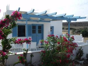 a white house with blue doors and pink flowers at Milithos Apartments 1 in Adamantas