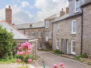 a row of brick houses with pink flowers in the foreground at Mermaid Cottage in Penzance