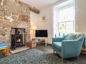 a living room with a stone fireplace and a blue chair at Mermaid Cottage in Penzance
