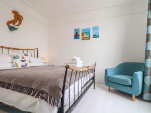 a bedroom with a bed and a blue chair at Mermaid Cottage in Penzance