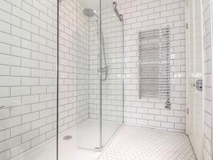 a bathroom with a glass shower with white tiles at Mermaid Cottage in Penzance +28 photos