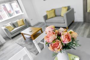 eine Vase mit rosa Rosen auf einem Tisch im Wohnzimmer in der Unterkunft Woodstock House - A Spacious Apartment Block with 9 Two-Bedroom Flats in Hucknall
