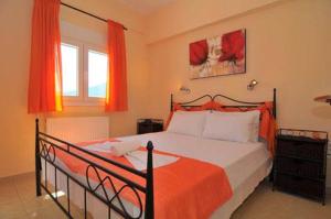 a bedroom with a large bed with an orange blanket at Nestor Apartments in Chrysi Ammoudia