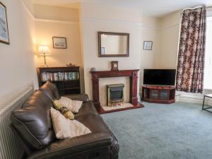 a living room with a leather couch and a fireplace at Sunnyside Holiday Apartment 1 in Bridlington