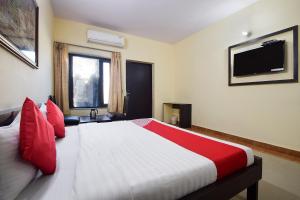a bedroom with a large bed with red pillows and a television at OYO 24408 Nirmala Guest House in Jodhpur