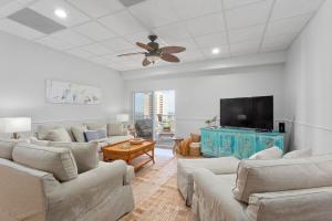 a living room with couches and a flat screen tv at Ocean Front Penthouse Suite Panoramic Views of Gulf,Pensacola Beach,Pier, & Bay in Pensacola Beach