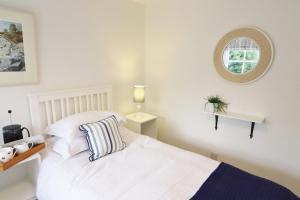a white bedroom with a bed and a mirror at 14 Union Street in Kirkcudbright