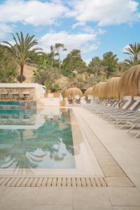 a pool at a resort with chairs and palm trees at Hotel Bahia del Sol in Santa Ponsa