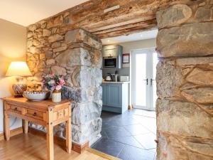 een stenen muur in een keuken met een houten tafel bij Beudy Penarddwnion in Dolgellau