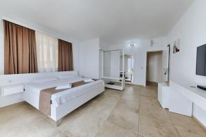 a white bedroom with a large bed and a television at MonteCasa Seaview Rooms in Dobra Voda