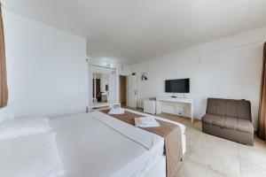 a white bedroom with a bed and a chair at MonteCasa Seaview Rooms in Dobra Voda