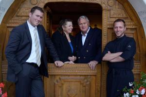 a group of three people standing behind a wooden door at Schlosshotel Chastè in Tarasp