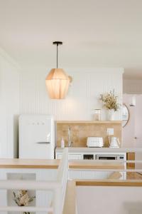 a kitchen with white appliances and a pendant light at The Sunsetter by WB Abodes in Wrightsville Beach