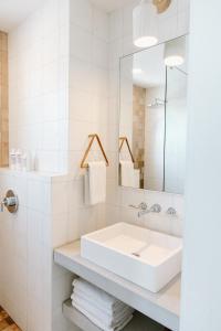 ein weißes Badezimmer mit einem Waschbecken und einem Spiegel in der Unterkunft The Sunsetter by WB Abodes in Wrightsville Beach