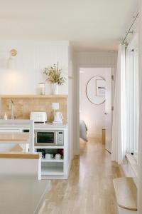 a white kitchen with a sink and a microwave at The Sunsetter by WB Abodes in Wrightsville Beach