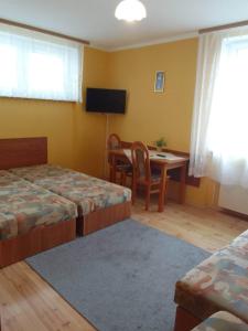 a bedroom with two beds and a table and a television at Pokoje ANNA in Rewal