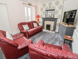 a living room with red leather furniture and a fireplace at Gwyder in Penmaen-mawr