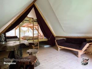 Habitación con tienda de campaña, cama y mesa. en Parc animalier du Hérisson en Doucier