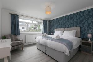 a bedroom with a bed and a chair and a window at Ocean Air in Carbis Bay