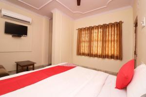 1 dormitorio con 1 cama blanca y TV en Flagship Hotel Midtown, en Bhopal