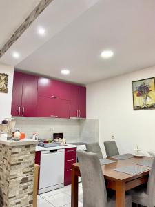 a kitchen with red cabinets and a wooden table at Apartman Guberinic,Tivat ,trosoban stan in Tivat