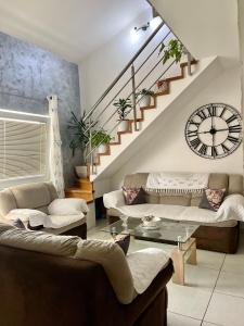 a living room with couches and a clock on the wall at Apartman Guberinic,Tivat ,trosoban stan in Tivat