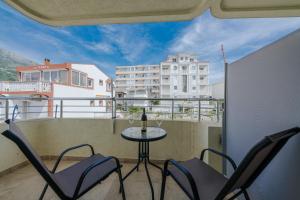 a balcony with a table and chairs and a building at MonteCasa Seaview Rooms in Dobra Voda
