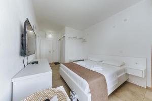 a white bedroom with a bed and a tv at MonteCasa Seaview Rooms in Dobra Voda