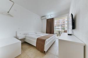 a white room with a bed and a television at MonteCasa Seaview Rooms in Dobra Voda