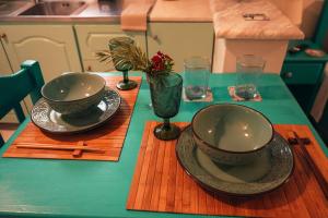 a table with two bowls and plates on a green table at Mojo Studios Parga in Parga