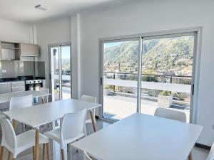 una cocina con mesas y sillas blancas y una gran ventana en VENETO V DEPARTAMENTOS en Villa Carlos Paz