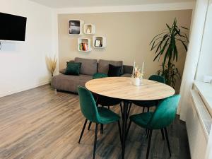 a living room with a table and green chairs at Ferienwohnung Schwarzwald Lodge in Schömberg