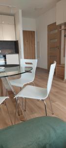 comedor con sillas blancas y mesa de cristal en nowy apartament en Ciechocinek