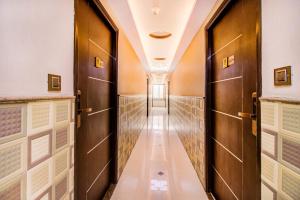 a corridor with wooden doors in a building at Capital O 5381 The Emirates Hotel in Bangalore