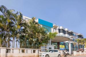 a car parked in front of a building with palm trees at Collection O 10885 Hotel Keerthana International in Kammasandra