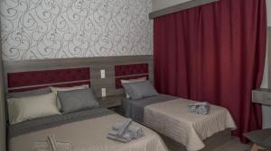 een kamer met 2 bedden en een rood gordijn bij Senia Holidays in Preveza