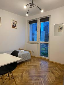 une chambre avec un lit et une table et deux fenêtres dans l'établissement HALBY rooms Pańska 55, à Varsovie