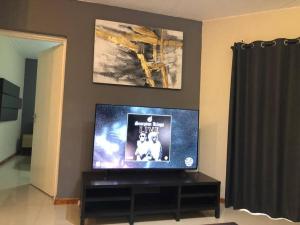 A homely and secure 2 bedroom with uncapped Wifi في جوهانسبرغ: تلفزيون بشاشة مسطحة جالس على منصة في غرفة المعيشة
