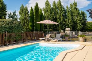 a swimming pool with two chairs and an umbrella at Hôtel Parc Adélie - Logis Hôtels in Montagny-lès-Beaune